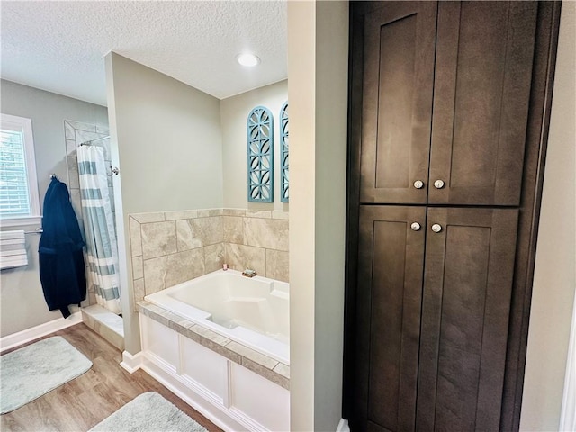 bathroom featuring shower with separate bathtub, a textured ceiling, and hardwood / wood-style flooring