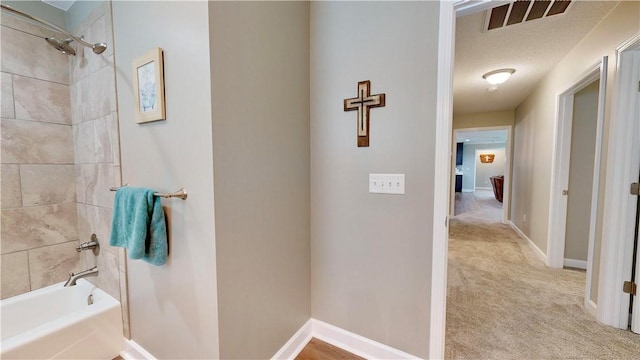 bathroom with a textured ceiling and tiled shower / bath