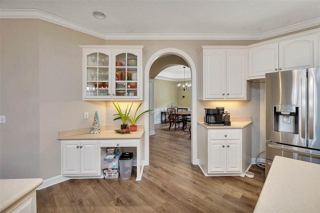 kitchen with stainless steel fridge with ice dispenser, hardwood / wood-style flooring, white cabinetry, and ornamental molding