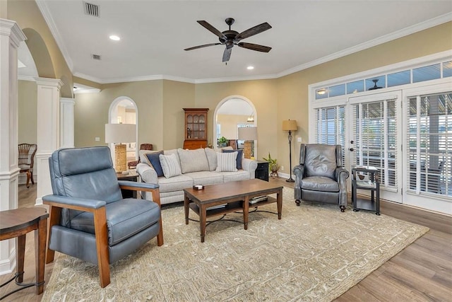 living room with decorative columns, hardwood / wood-style floors, crown molding, and ceiling fan