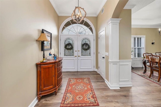 foyer featuring hardwood / wood-style floors, decorative columns, a notable chandelier, and plenty of natural light