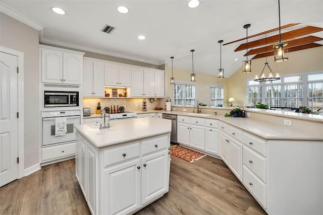 kitchen with white cabinets, stainless steel appliances, an island with sink, and decorative light fixtures