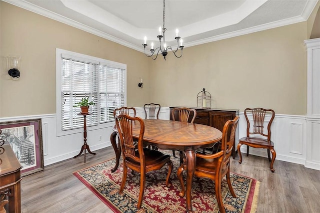 dining area with a chandelier, hardwood / wood-style floors, crown molding, and a tray ceiling