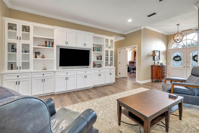 living room with light hardwood / wood-style floors, french doors, crown molding, and a chandelier