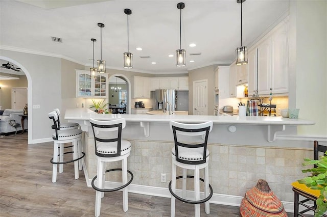 kitchen with decorative light fixtures, white cabinetry, kitchen peninsula, and a kitchen breakfast bar