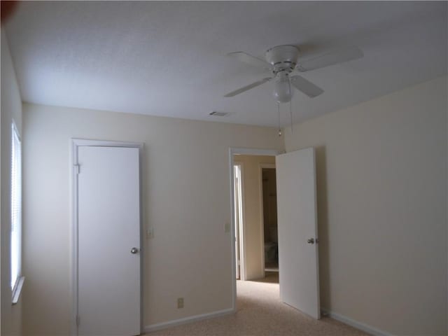 unfurnished bedroom with multiple windows, light colored carpet, and ceiling fan