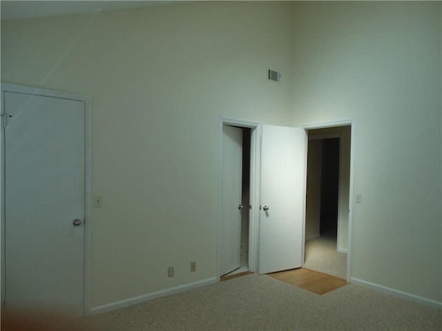 unfurnished bedroom with a towering ceiling and light carpet