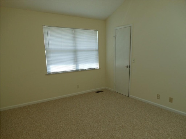 carpeted empty room with vaulted ceiling