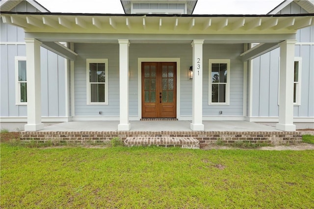 231 Salt Creek Way E, Brunswick, GA 31523 - view of exterior entry featuring board and batten siding, covered porch, and a lawn