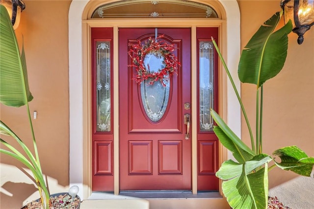 property entrance featuring a porch and stucco siding