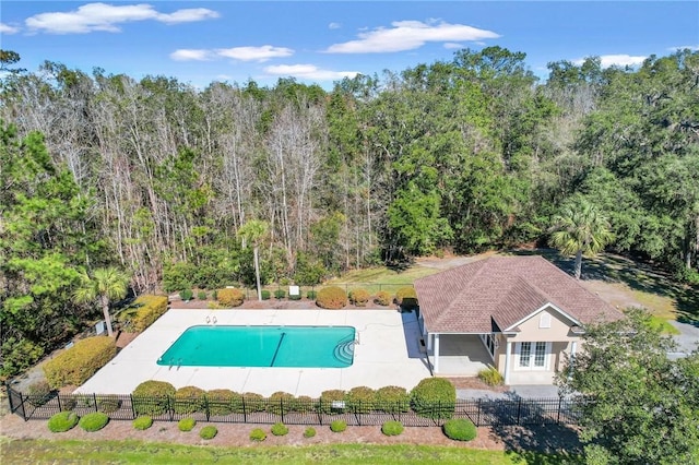 view of swimming pool featuring a fenced in pool, fence private yard, a patio area, and a view of trees