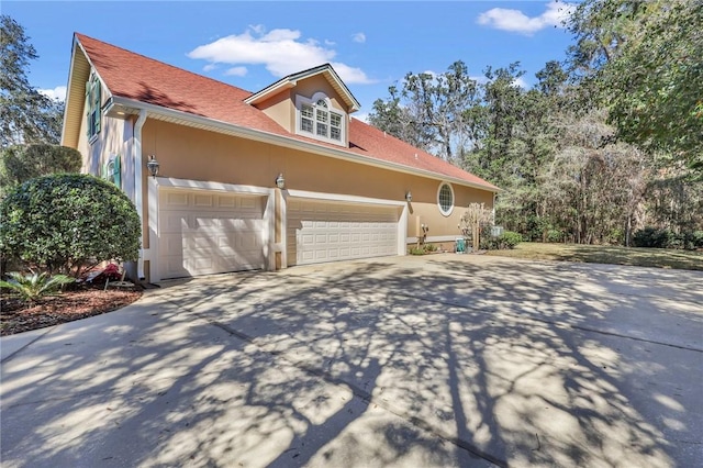 view of side of home with an attached garage, concrete driveway, and stucco siding