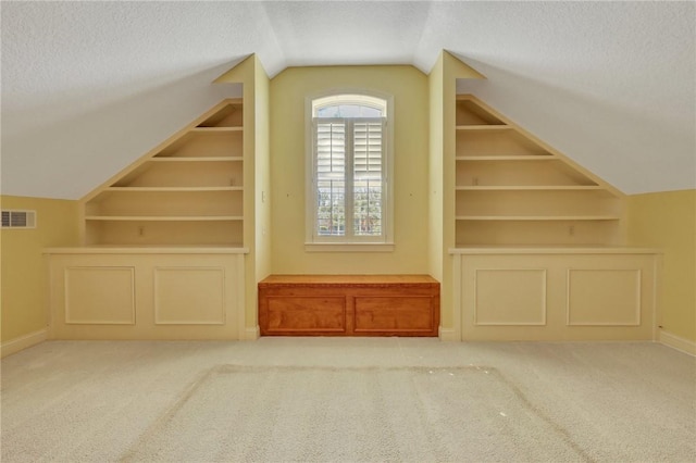 bonus room featuring built in shelves, visible vents, and a textured ceiling