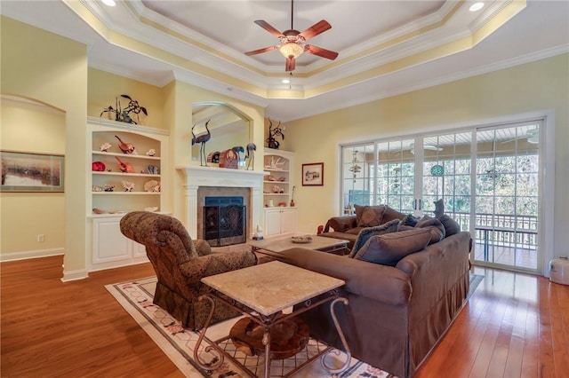 living room featuring a healthy amount of sunlight, a tray ceiling, and wood finished floors