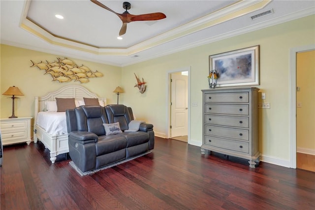 bedroom featuring wood finished floors, visible vents, baseboards, ornamental molding, and a raised ceiling