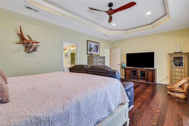 bedroom featuring connected bathroom, visible vents, ornamental molding, a tray ceiling, and hardwood / wood-style floors