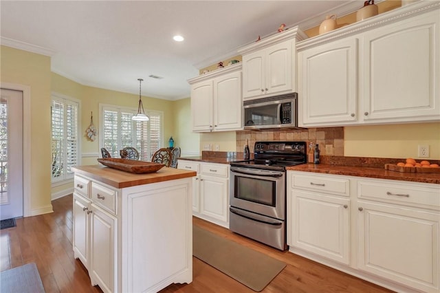 kitchen featuring stainless steel appliances, light wood-style floors, wooden counters, ornamental molding, and decorative backsplash