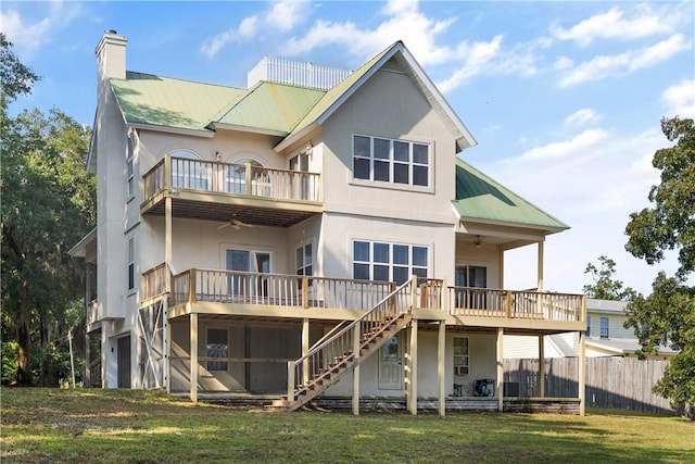 rear view of house with ceiling fan, a yard, a balcony, and a garage