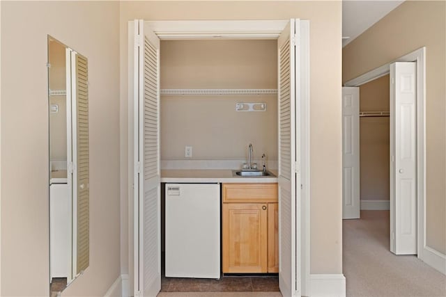 bar with dishwasher, light brown cabinets, and sink