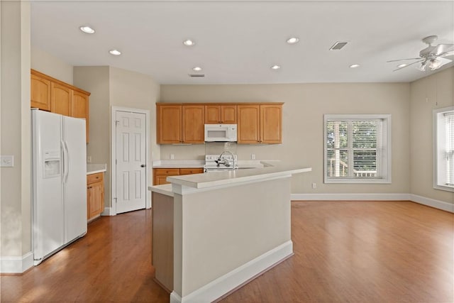 kitchen featuring white appliances, a kitchen island with sink, ceiling fan, sink, and wood-type flooring