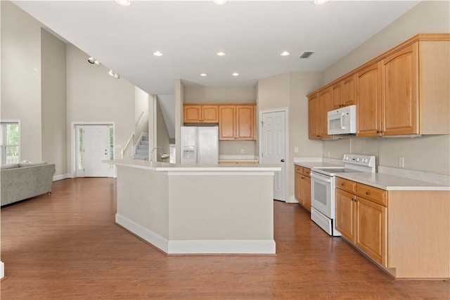 kitchen with hardwood / wood-style floors, white appliances, a center island with sink, and sink