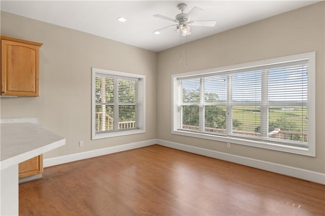 unfurnished dining area with ceiling fan and wood-type flooring