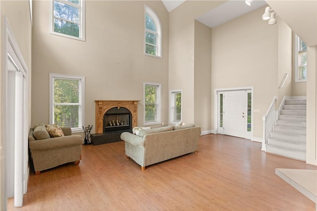 living room featuring light wood-type flooring and a towering ceiling