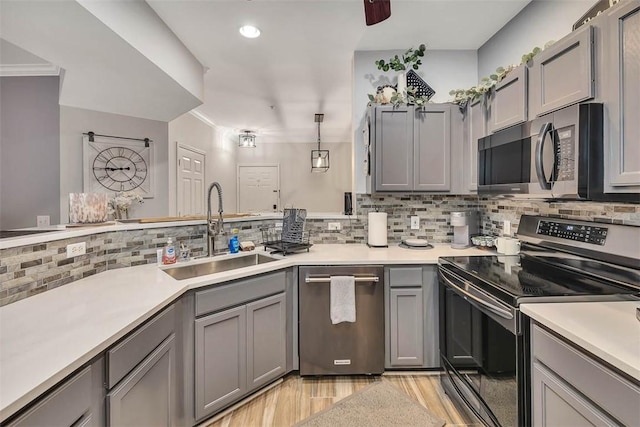 kitchen featuring stainless steel appliances, pendant lighting, light countertops, and a sink