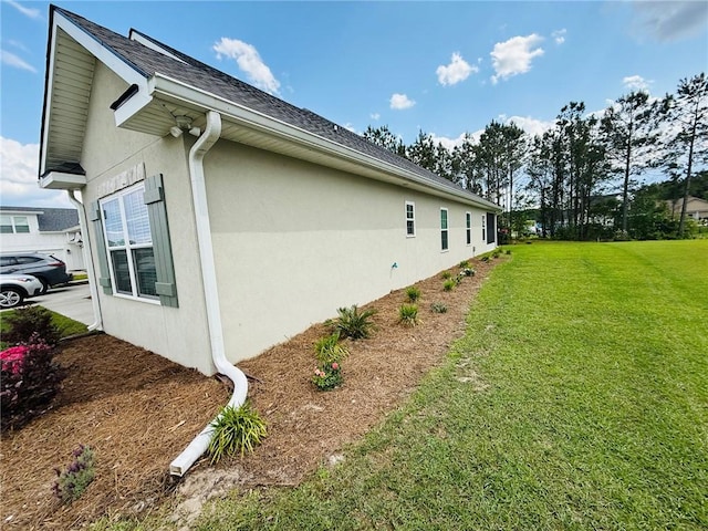 156 Allie Loop, Brunswick, GA 31525 - view of home's exterior featuring stucco siding, a lawn, and roof with shingles
