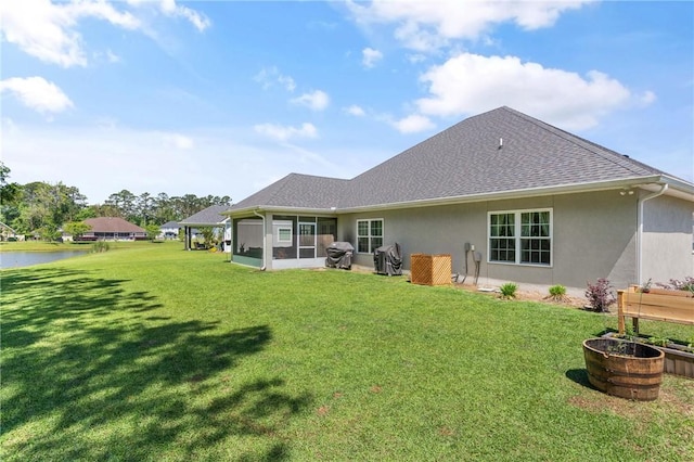 156 Allie Loop, Brunswick, GA 31525 - back of house with stucco siding, a yard, a sunroom, a shingled roof, and a water view