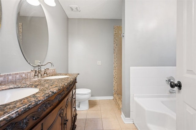 bathroom with tile patterned floors, a tub to relax in, a textured ceiling, toilet, and vanity