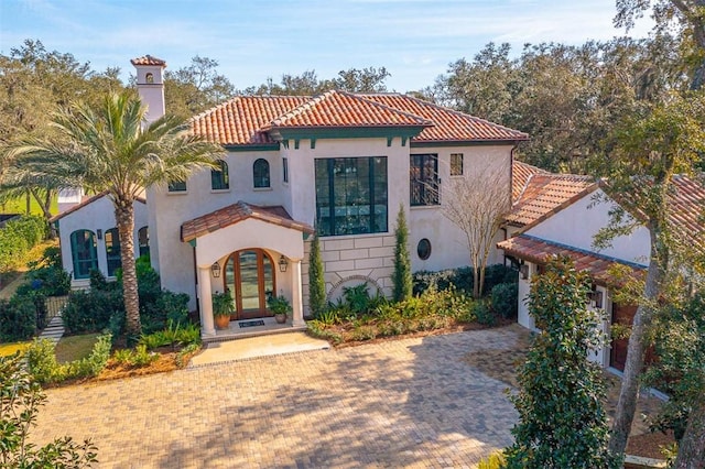 mediterranean / spanish-style house featuring stucco siding, a tiled roof, and french doors