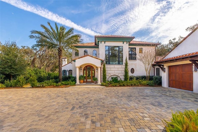 mediterranean / spanish-style house featuring a garage, french doors, a tiled roof, and stucco siding