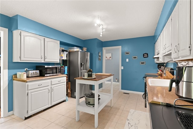 4936 US Highway 17 N, Brunswick, GA 31525 - kitchen with stainless steel appliances, a textured ceiling, white cabinetry, light tile patterned floors, and light countertops