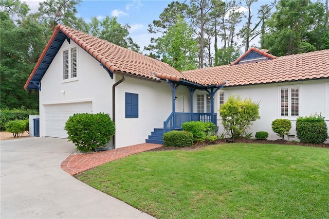 mediterranean / spanish home featuring a tile roof, a front yard, driveway, and stucco siding