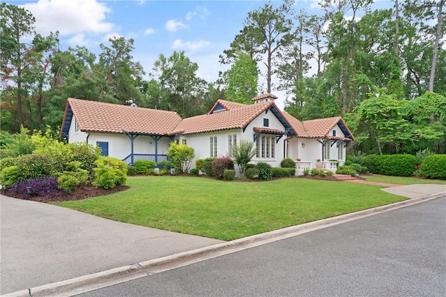 mediterranean / spanish home with a tiled roof, a front yard, and stucco siding