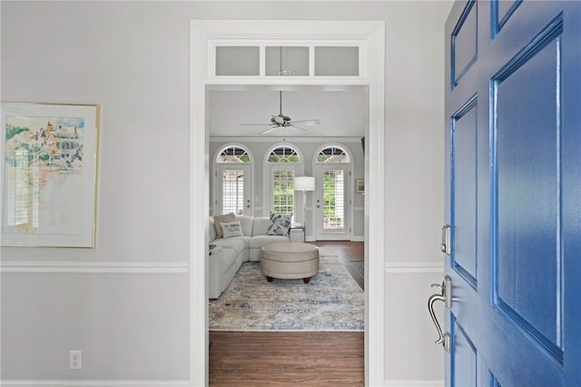 foyer entrance featuring wood finished floors, a ceiling fan, and baseboards