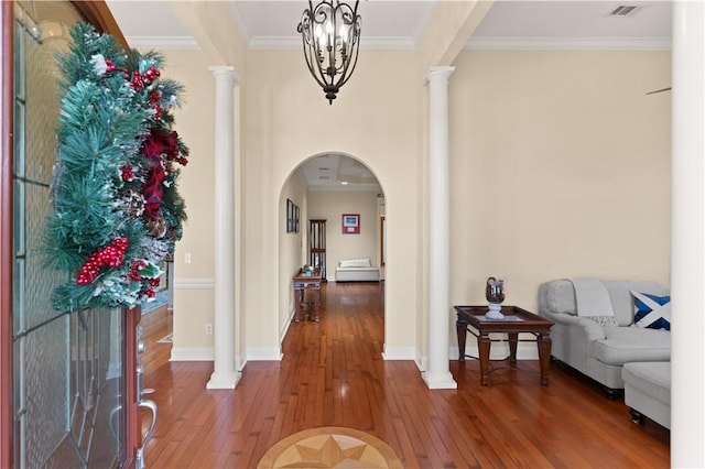 entrance foyer featuring ornate columns, crown molding, a notable chandelier, and hardwood / wood-style flooring