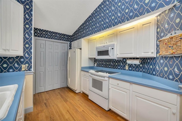 40 W Lake Dr, Saint Simons Island, GA 31522 - kitchen featuring wallpapered walls, white appliances, lofted ceiling, light wood-type flooring, and white cabinetry