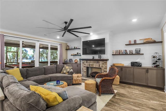 living room with crown molding, a brick fireplace, wood-type flooring, and ceiling fan