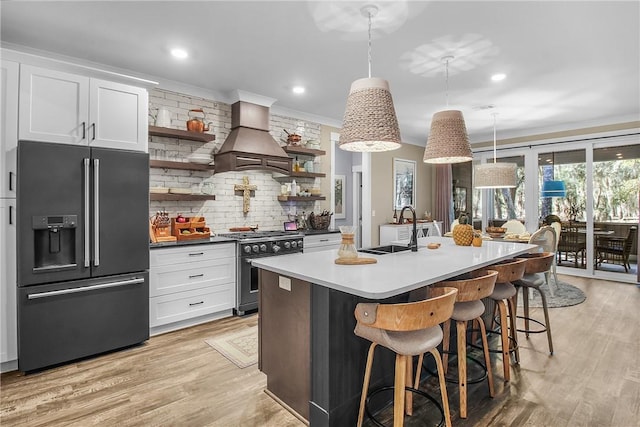 kitchen featuring premium range hood, pendant lighting, sink, white cabinets, and high end appliances