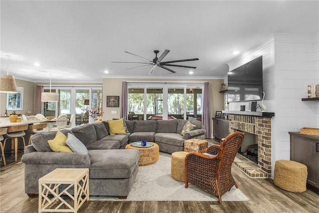 living room with hardwood / wood-style flooring, ornamental molding, and a brick fireplace