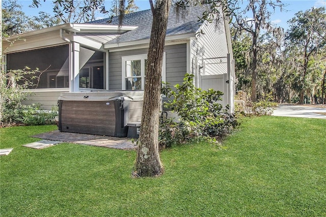 view of home's exterior with a yard, a sunroom, and a hot tub