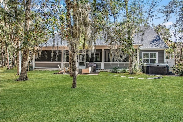 back of house with cooling unit, a yard, and a hot tub