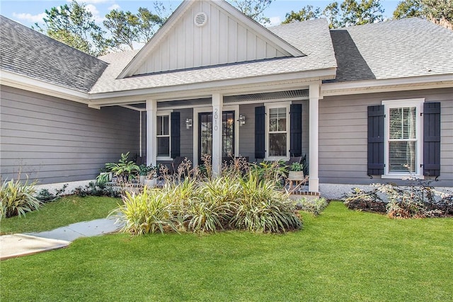 entrance to property with a yard, board and batten siding, roof with shingles, and a porch