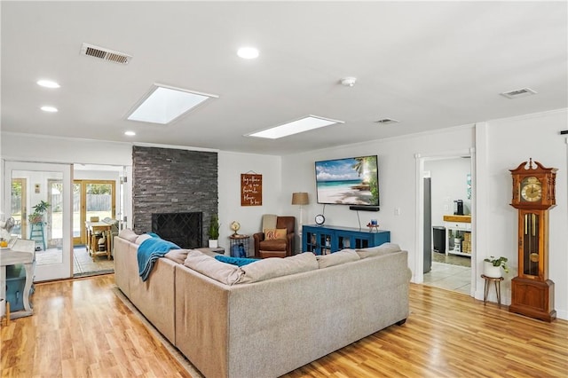 408 Couper Ave, Saint Simons Island, GA 31522 - living room featuring a stone fireplace, light wood finished floors, crown molding, a skylight, and recessed lighting