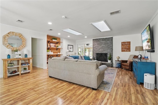 408 Couper Ave, Saint Simons Island, GA 31522 - living room with light wood-style flooring, a stone fireplace, ornamental molding, recessed lighting, and a skylight
