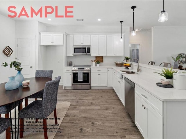 kitchen with pendant lighting, sink, light wood-type flooring, white cabinetry, and stainless steel appliances