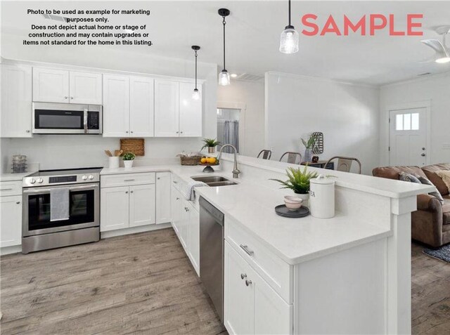 kitchen with pendant lighting, white cabinets, sink, kitchen peninsula, and stainless steel appliances