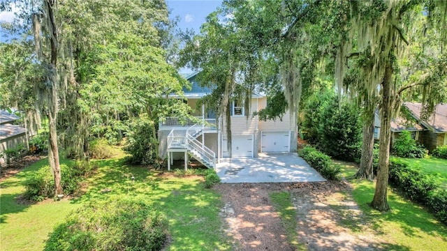 exterior space featuring stairs, a lawn, an attached garage, and driveway